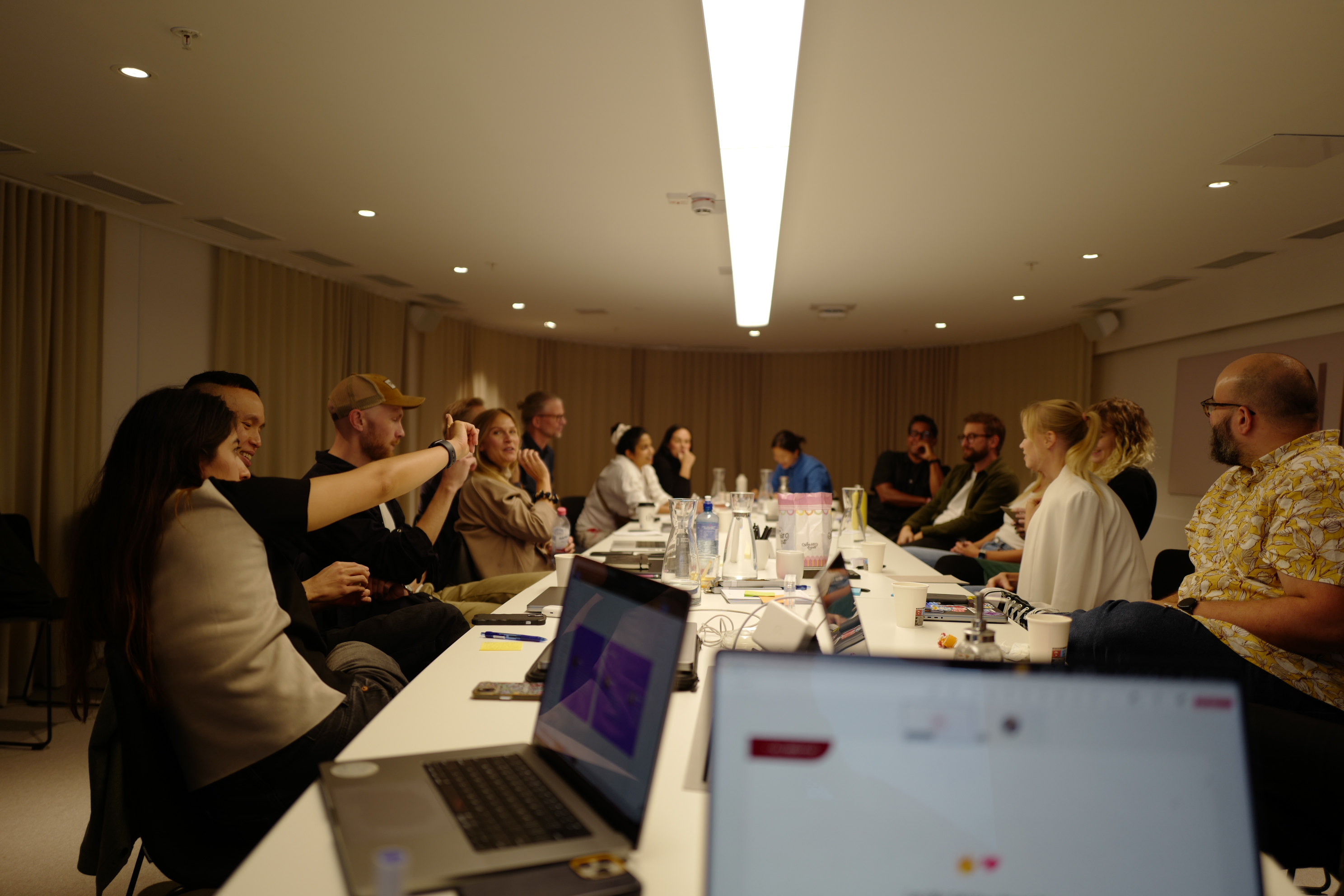 Team members gathered around a conference table during a UX offsite, with laptops and workshop materials.
